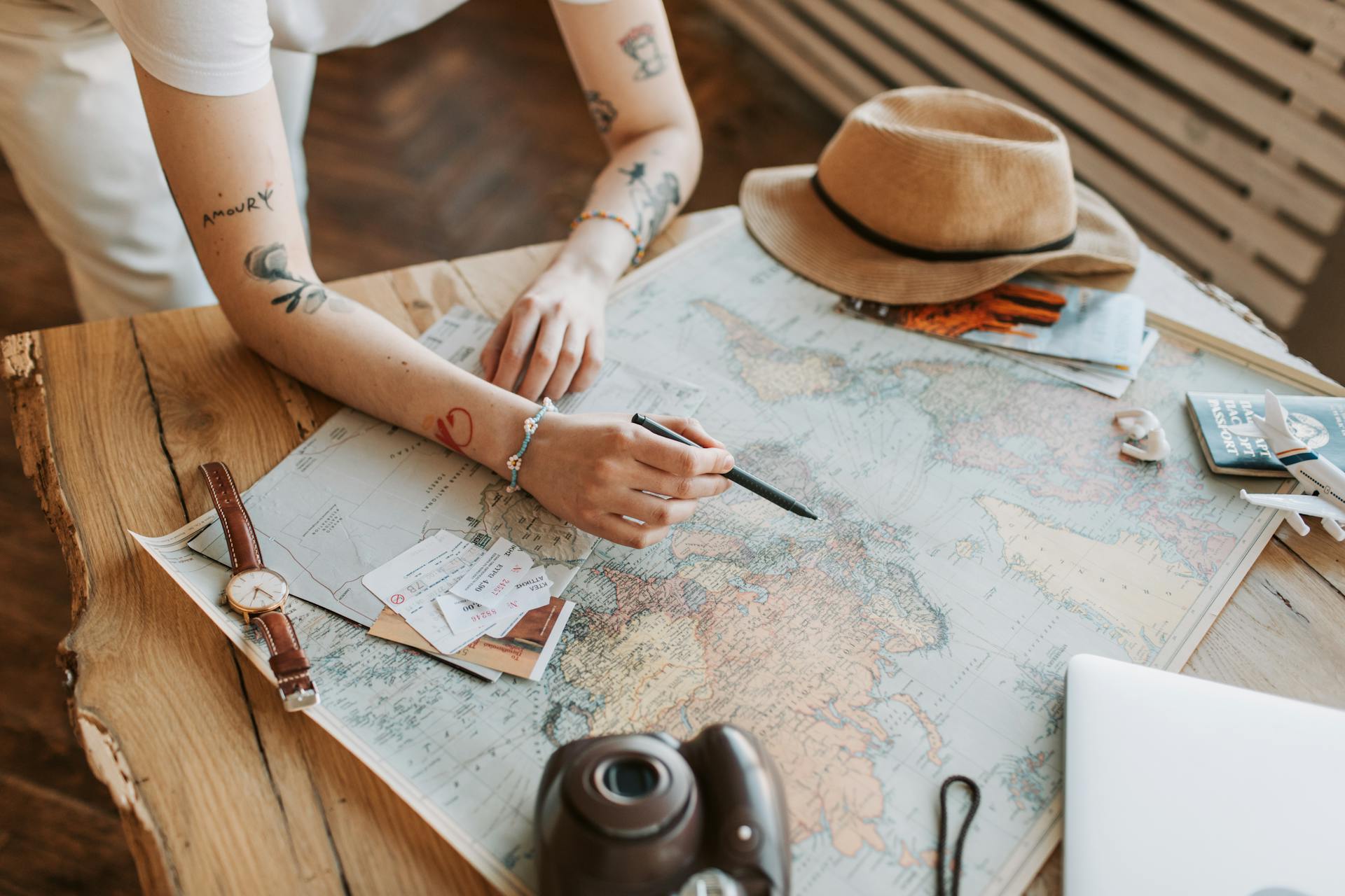 A person checking a world map on a table surrounded by personal items