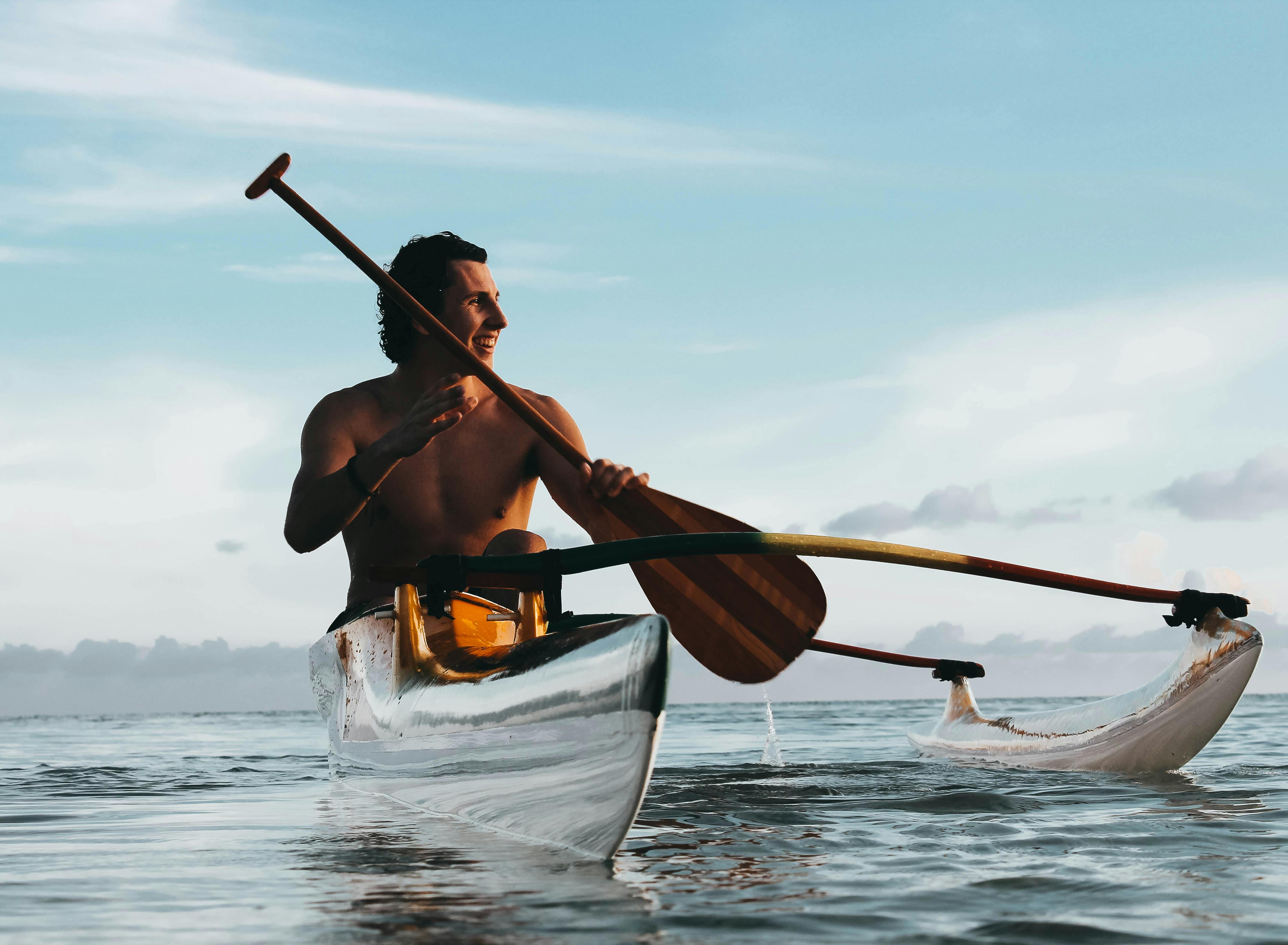 A person holding a paddle while riding on a kayak at sea
