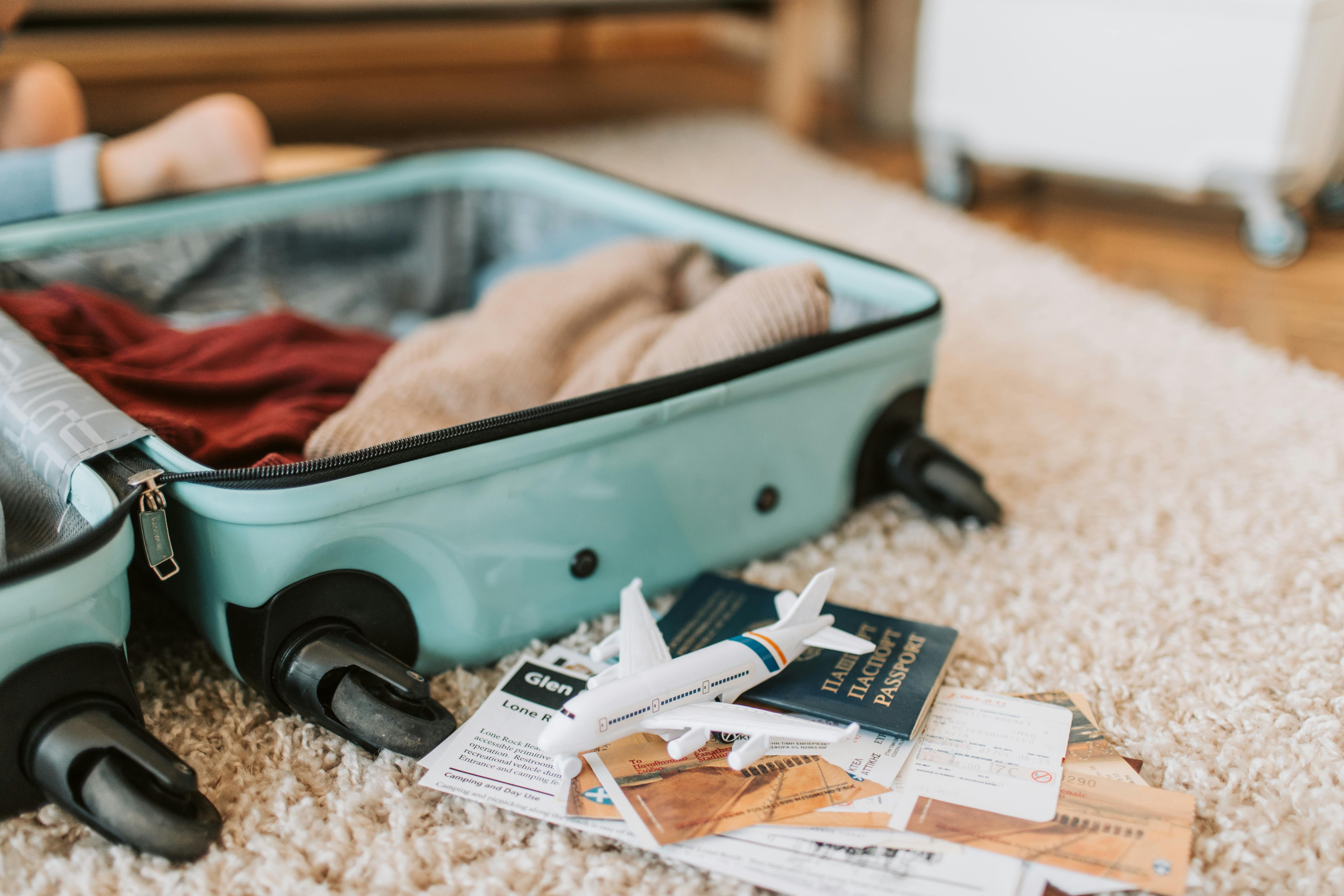 A luggage bag on a brown carpet next to plane tickets and a passport